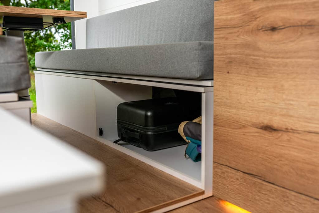 Rear luggage compartment with removable storage panel in The Biggie campervan