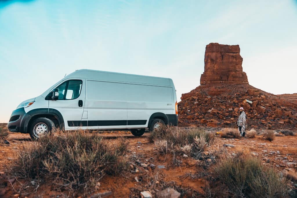 Exterior of The Biggie campervan parked near red rock formations in the American West