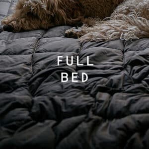 Dog sleeping on a full bed on a Rumpl blanket.