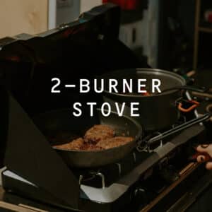 Cooking burgers on a dual burner stove in the kitchen of the Squad Campervan